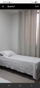 a bed in a bedroom with a white curtain at Casa Tranquila em Diamantina in Diamantina