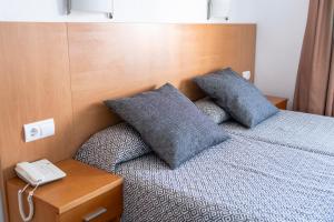 a bedroom with a bed with two pillows and a phone at Primavera Loix in Benidorm