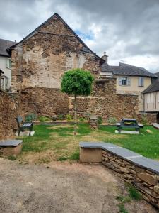 a stone building with two benches and a tree at - L'abri correzien - Cœur de cité médiévale in Donzenac