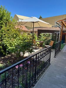 a fence with an umbrella and a table and benches at Eötvös Apartman in Cegléd