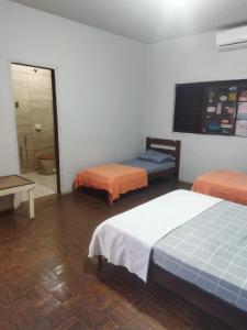 a room with two beds and a door to a bathroom at Cantinho da Flor in Barretos