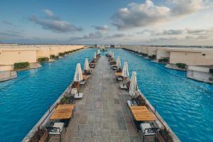 a long row of tables and umbrellas in the water at Azur White Resort Ras El Hekma in Zāwiyat al ‘Awwāmah