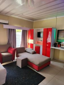 a room with a bed and a couch and a chair at The wood Guest house in Pretoria
