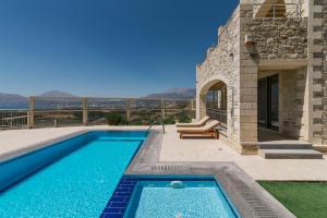 a swimming pool in the backyard of a house at Villa Ovgoro - Luxury 3-Level Villa with Heated Pool, Jacuzzi and Panoramic Views in Kamilari