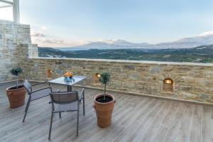 a patio with a table and chairs and a stone wall at Villa Ovgoro - Luxury 3-Level Villa with Heated Pool, Jacuzzi and Panoramic Views in Kamilari