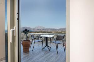 a table and chairs on a balcony with a view at Villa Ovgoro - Luxury 3-Level Villa with Heated Pool, Jacuzzi and Panoramic Views in Kamilari +51 photos