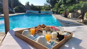 a tray of food with orange juice and eggs next to a swimming pool at 15min de la Cité de Carcassonne dans petit village, chambre au calme, petit-déjeuner et jacuzzi en supplément in Carcassonne
