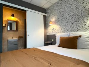 a bedroom with a large bed and a bathroom at Hôtel Maisons Delphine - Le Cottage in Villers-sur-Mer