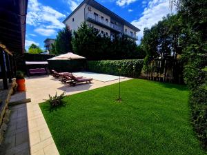 a lawn with benches and an umbrella in a yard at Vila Eclipse Mamaia nord in Mamaia Sat/Năvodari