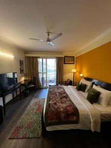 a hotel room with a large bed and a desk at ALOHA DIVINE GANGES APARTMENTS with INFINITY POOL in Rishīkesh