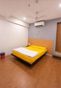 a yellow bed in a room with a wooden floor at Hotel Bluesky in Surat