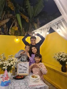 a group of people standing next to a table with a cake at Snow Homestay in Ninh Binh