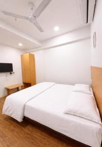 a bedroom with a white bed and a tv at Hotel Bluesky in Surat