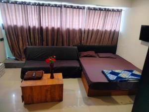 a room with a bed and a couch and a table at Hotel Bluesky in Surat +3 photos