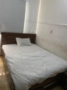 a bed with white sheets and a pillow on it at Beulah House Lounge in Ibadan