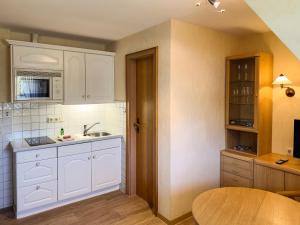 a kitchen with white cabinets and a wooden table at Haus *Üüs Aran* Wohnung Nr. 6 in Nebel