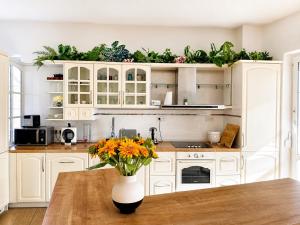 eine Küche mit weißen Schränken und ein Tisch mit Blumen in der Unterkunft Biomade in Prag + 8 Fotos