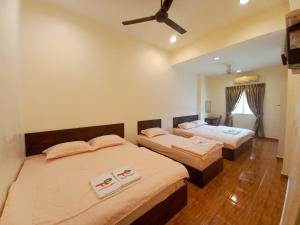 a bedroom with two beds and a ceiling fan at mulia homestay in Teluk Intan