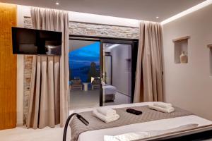a bedroom with a bed and a large window at Pnoe Villas Syros in Megas Gialos - Nites