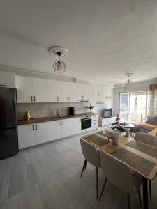 a kitchen with white cabinets and a table and a couch at InnPogradec Center in Pogradec