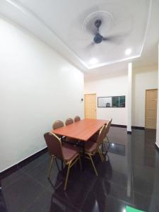 a dining room with a wooden table and chairs at mulia homestay in Teluk Intan