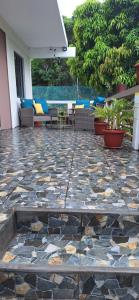 a patio with a stone floor with chairs and tables at Oasis Mountain Retreat in Le Morne