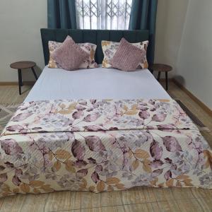 a large bed with a floral comforter and pillows at Oasis Mountain Retreat in Le Morne