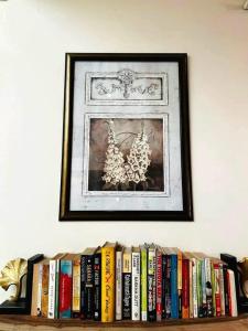 a shelf of books with a picture on the wall at Chinar Homes Amritsar in Amritsar