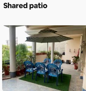 a table and chairs under an umbrella on a patio at Chinar Homes Amritsar in Amritsar