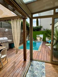 a patio with a swimming pool and a wooden deck at Jasmin House in Cenon