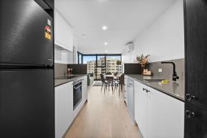 a kitchen with white cabinets and a black refrigerator at Premium 2BR Braddon, Marriott Amenities in Braddon