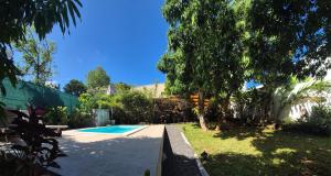 a backyard with a swimming pool and trees at Ti case Margot - Maison avec piscine à Manapany in Saint-Joseph