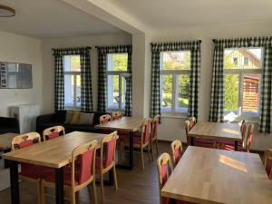 a restaurant with wooden tables and chairs and windows at Penzion Hají in Janov nad Nisou