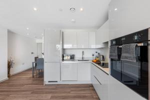 a white kitchen with black and white appliances at Duplex 2BR Flat with Parking Near Excellent Transport Links By Stay Aura Short Term Lets Brentford in Brentford