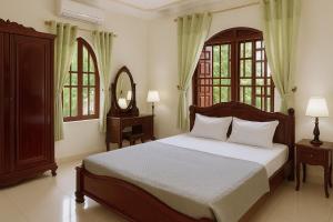 a bedroom with a bed and a mirror and windows at Pham's Homestay in Île de Trà Cổ