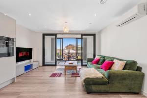 a living room with a green couch and a tv at Duplex 2BR Flat with Parking Near Excellent Transport Links By Stay Aura Short Term Lets Brentford in Brentford