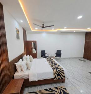 a bedroom with a large bed and two chairs at Hotel Sooryavanshi in Ayodhya