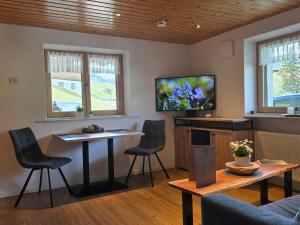 a living room with a table and chairs and a tv at Walser Auszeit in Riezlern