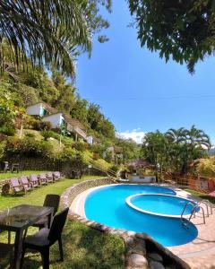 a swimming pool in a yard with chairs and a table at Fundo San Jose Parque Ecológico & Lodge Hotel Asociado Casa Andina in La Merced