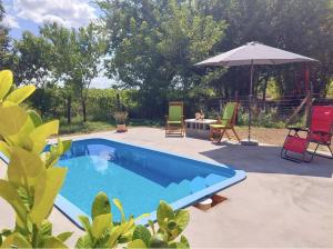 a swimming pool with a table and chairs and an umbrella at Vidam in Csengőd