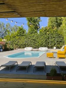 a swimming pool with benches and a yellow chair at Appartamento con Vista Mare e Piscina a Casa Vuscichè in Roseto degli Abruzzi