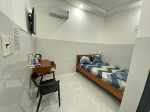a bedroom with a bed and a table and a chair at Nhà Nghỉ Phi Yến in Phụng Hiệp