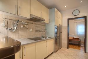 a kitchen with white cabinets and a sink and a clock at Pansion 22 CETINJE in Cetinje