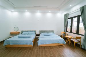 a bedroom with two beds and a table and chairs at Đồi Bông Village in Mục Uyên