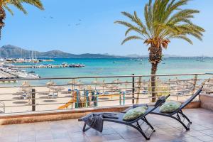 a pair of chairs sitting on a balcony overlooking a beach at Apartment VistaMar I in Port de Pollensa
