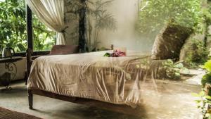 a bed with a white comforter and flowers on it at Neverland de Papillons in Sa Ðéc