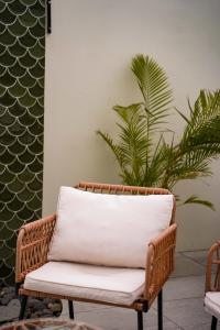 a wicker chair with a white cushion in front of a plant at Anba Solēy in Surinam