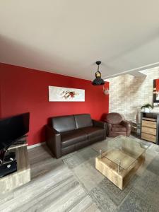 a living room with a leather couch and a red wall at The2 Work or holiday apartment in Godshuis
