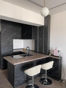 a kitchen with black marble counter and two bar stools at Soho Apartment Fial in Bacău