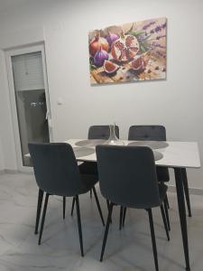 a dining room table with chairs and a painting on the wall at Apartman Herceg in Ljubuški